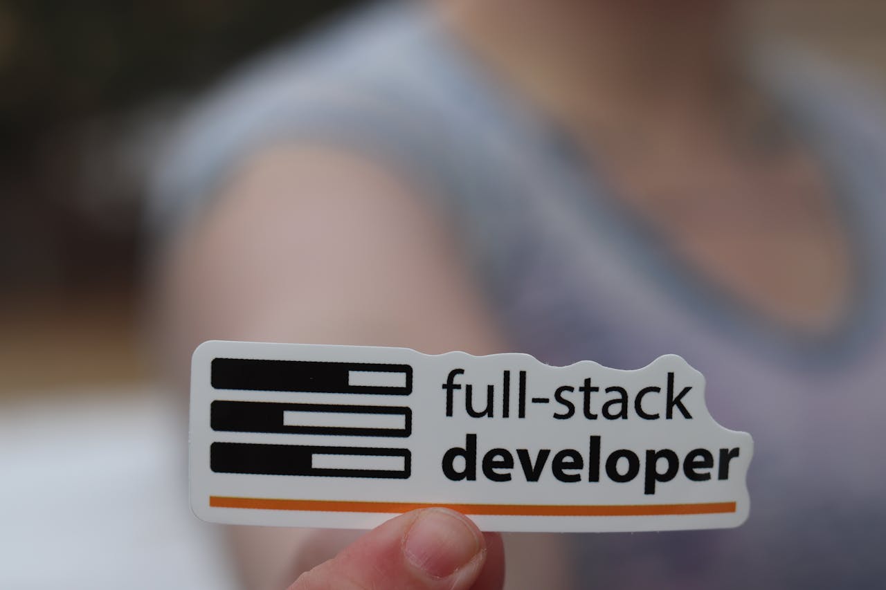journey A hand holding a sticker labeled 'full-stack developer', symbolizing technology and programming skills.